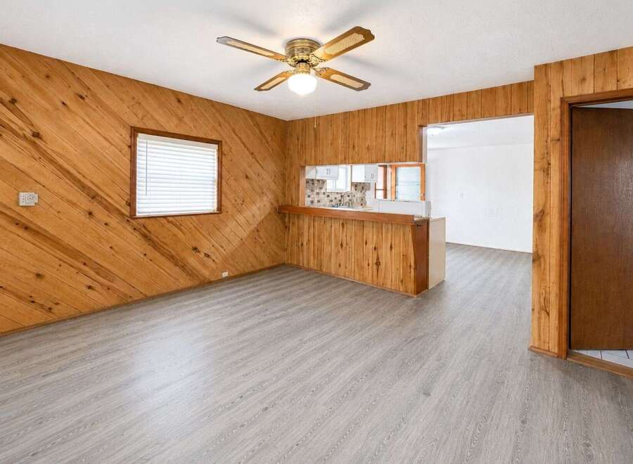 Step into this charming living space featuring warm wood-paneled walls and a convenient breakfast bar overlooking the kitchen.