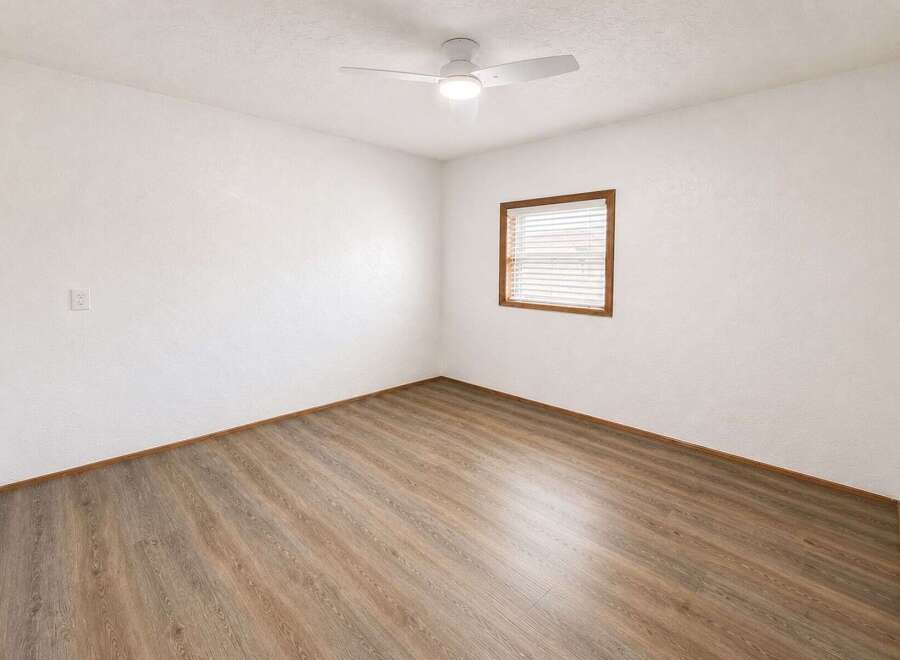 This empty room features a modern white ceiling fan with integrated lighting, perfect for maintaining a comfortable atmosphere.