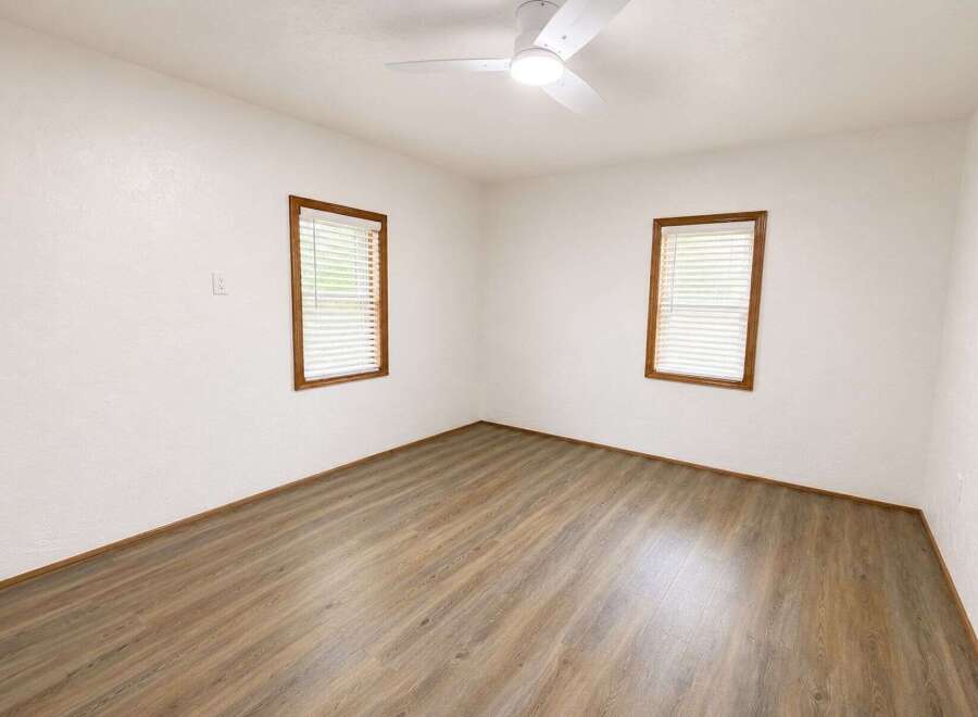 Discover this inviting room featuring a modern ceiling fan and two large windows that flood the space with natural light.