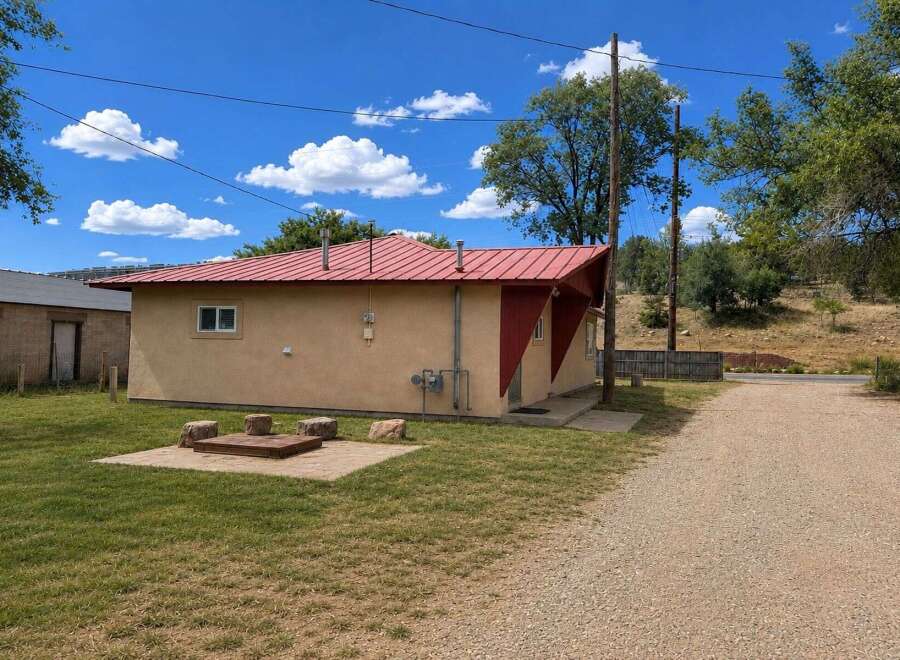 Discover this charming property featuring a vibrant red metal roof and a cozy outdoor fire pit area, perfect for relaxing evenings.