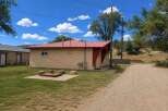 Discover this charming property featuring a vibrant red metal roof and a cozy outdoor fire pit area, perfect for relaxing evenings.
