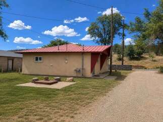 Discover this charming property featuring a vibrant red metal roof and a cozy outdoor fire pit area, perfect for relaxing evenings.