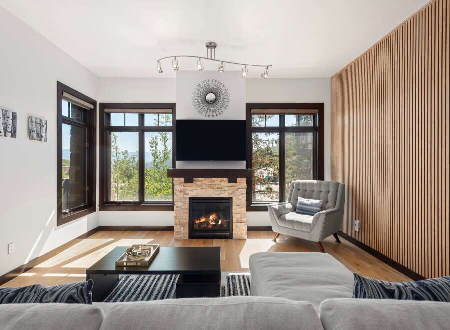 Experience modern living in this stunning living room featuring a cozy stone fireplace and a large flat-screen TV.