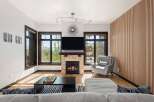 Experience modern living in this stunning living room featuring a cozy stone fireplace and a large flat-screen TV.