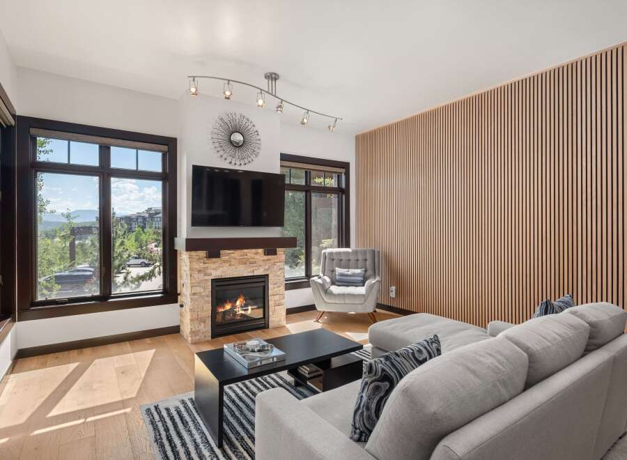 Experience modern mountain living in this stunning living room, featuring a cozy stone fireplace and a sleek entertainment center.
