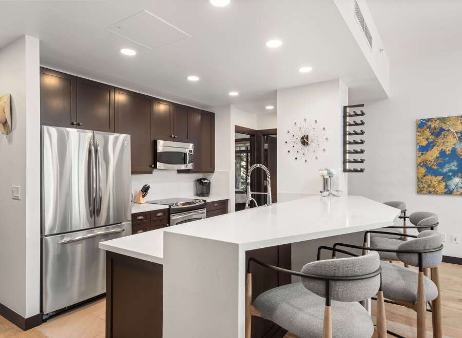 Experience modern living in this stunning kitchen, featuring sleek dark wood cabinetry and a spacious white quartz island perfect for entertaining.