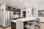 Experience modern living in this stunning kitchen, featuring sleek dark wood cabinetry and a spacious white quartz island perfect for entertaining.