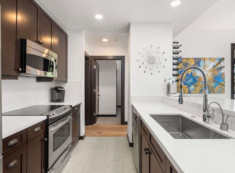 Experience modern living in this stunning kitchen, featuring sleek dark wood cabinetry and gleaming stainless steel appliances.