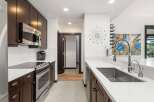 Experience modern living in this stunning kitchen, featuring sleek dark wood cabinetry and gleaming stainless steel appliances.