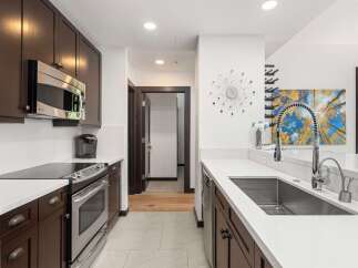 Experience modern living in this stunning kitchen, featuring sleek dark wood cabinetry and gleaming stainless steel appliances.