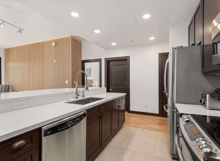 Experience modern living in this stunning kitchen featuring sleek dark wood cabinetry and a pristine white quartz countertop.
