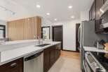 Experience modern living in this stunning kitchen featuring sleek dark wood cabinetry and a pristine white quartz countertop.