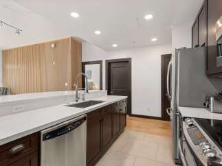 Experience modern living in this stunning kitchen featuring sleek dark wood cabinetry and a pristine white quartz countertop.