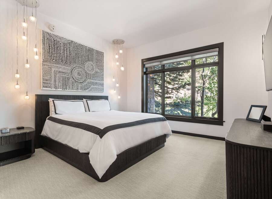 Experience luxury in this master bedroom featuring a king-sized bed with crisp white linens and elegant dark trim.