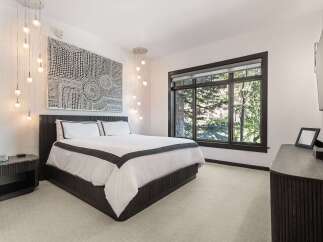 Experience luxury in this master bedroom featuring a king-sized bed with crisp white linens and elegant dark trim.