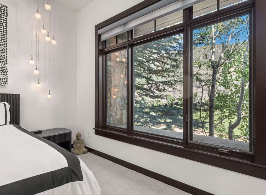 Experience serene mountain living in this beautifully appointed bedroom, featuring a plush bed and a multi-light pendant fixture.