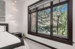Experience serene mountain living in this beautifully appointed bedroom, featuring a plush bed and a multi-light pendant fixture.