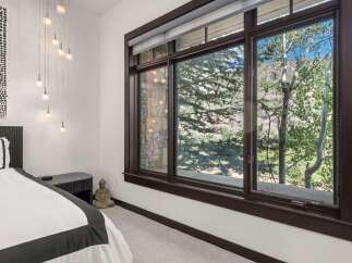 Experience serene mountain living in this beautifully appointed bedroom, featuring a plush bed and a multi-light pendant fixture.