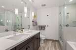 Experience modern luxury in this stunning bathroom featuring a dual vanity with sleek chrome fixtures and a spacious glass-enclosed shower.