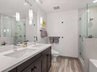 Experience modern luxury in this stunning bathroom featuring a dual vanity with sleek chrome fixtures and a spacious glass-enclosed shower.