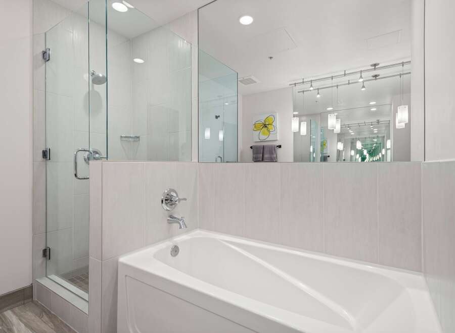 Experience modern luxury in this stunning bathroom, featuring a sleek glass-enclosed shower and a deep soaking tub perfect for relaxation.