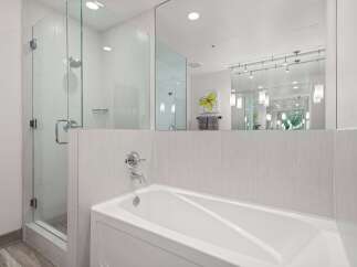 Experience modern luxury in this stunning bathroom, featuring a sleek glass-enclosed shower and a deep soaking tub perfect for relaxation.