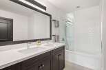 This modern bathroom features a sleek double vanity with chrome faucets and a large, dark-framed mirror.
