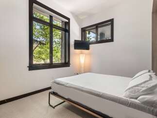 Experience serene living in this modern bedroom, featuring a comfortable bed adorned with crisp white linens and elegant grey trim.