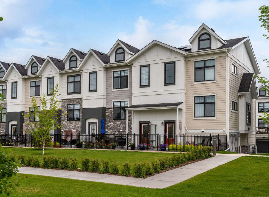 Discover modern townhome living in this stunning property featuring a multi-tone exterior with stone accents and sleek black window frames.