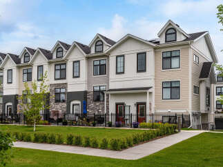 Discover modern townhome living in this stunning property featuring a multi-tone exterior with stone accents and sleek black window frames.