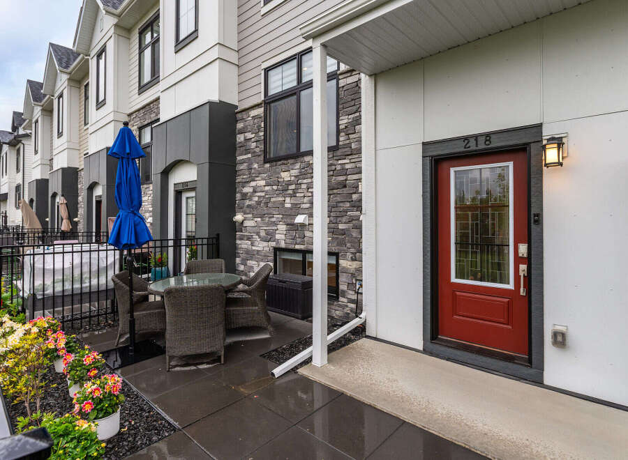 Enjoy outdoor living in this charming townhouse featuring a private patio with a dining set and a blue umbrella.