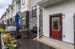 Enjoy outdoor living in this charming townhouse featuring a private patio with a dining set and a blue umbrella.