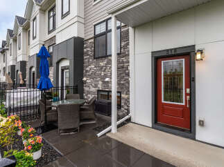Enjoy outdoor living in this charming townhouse featuring a private patio with a dining set and a blue umbrella.