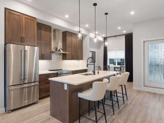 Experience modern living in this stunning kitchen, featuring rich wood cabinetry and sleek stainless steel appliances.
