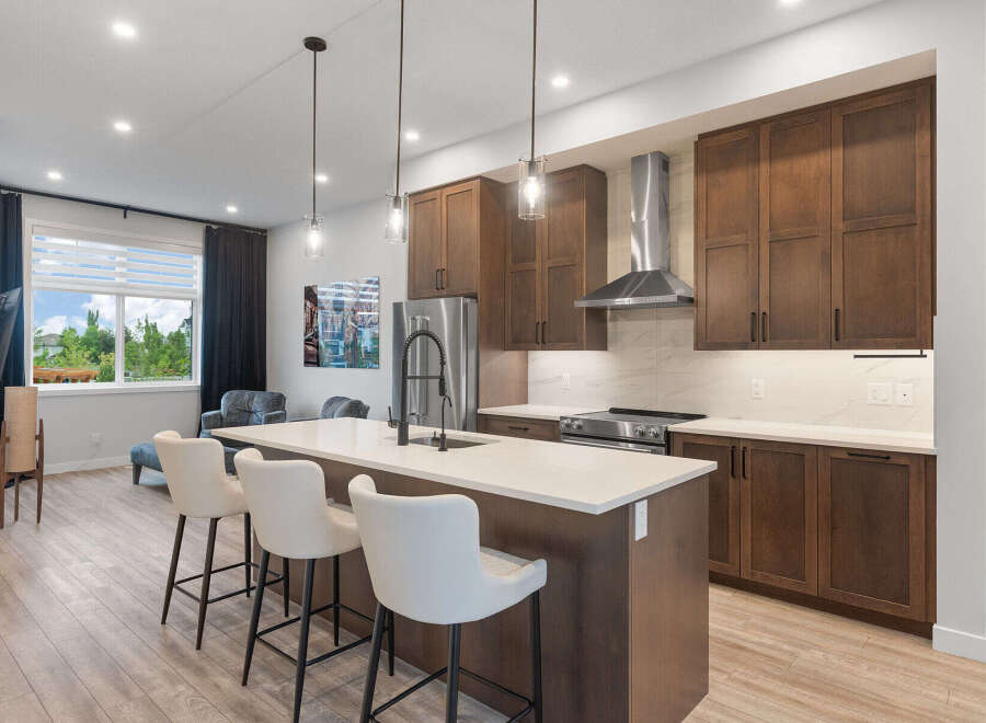 Experience modern living in this stunning kitchen featuring rich wood cabinetry and a sleek island with bar seating.