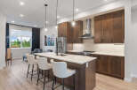 Experience modern living in this stunning kitchen featuring rich wood cabinetry and a sleek island with bar seating.