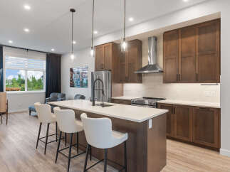 Experience modern living in this stunning kitchen featuring rich wood cabinetry and a sleek island with bar seating.