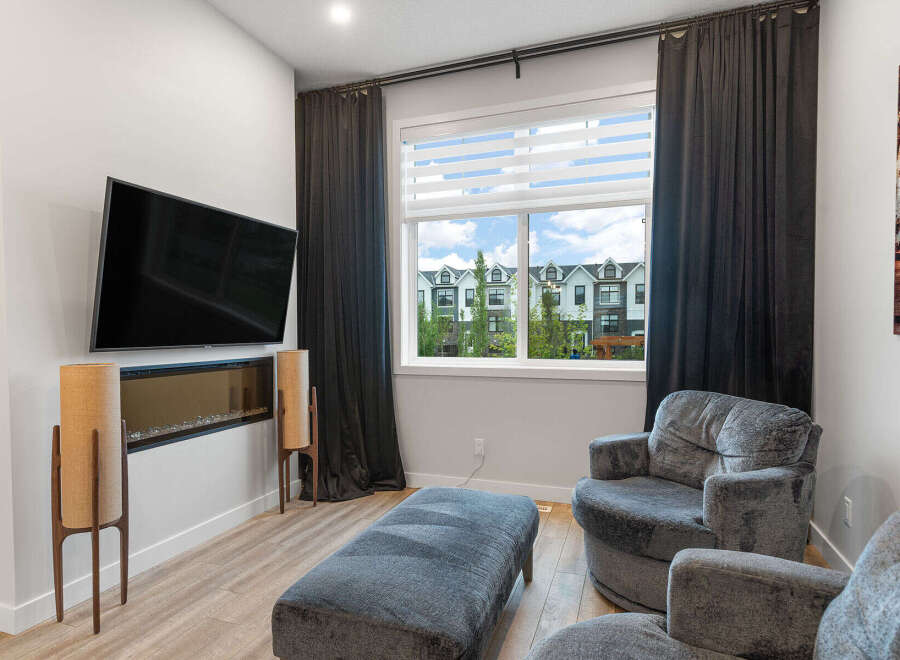 Experience modern living in this stylish living room, featuring a sleek wall-mounted television above a contemporary fireplace.