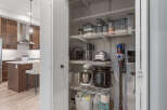 Discover ample storage in this well-organized pantry, featuring multiple shelves stocked with kitchen appliances and food containers.