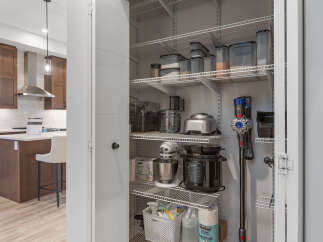 Discover ample storage in this well-organized pantry, featuring multiple shelves stocked with kitchen appliances and food containers.