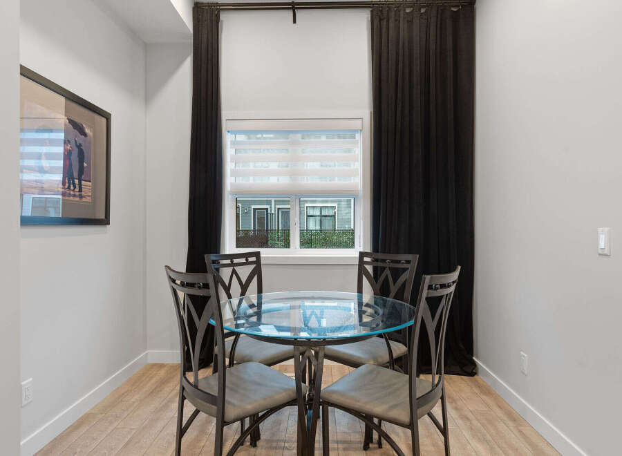 This dining area features a stylish glass-top table with four upholstered chairs, perfect for intimate meals.