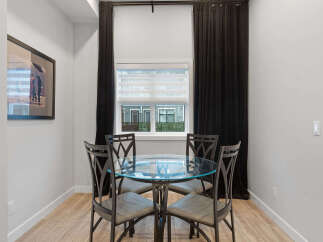 This dining area features a stylish glass-top table with four upholstered chairs, perfect for intimate meals.