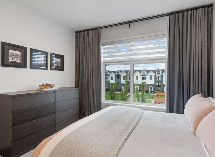 This bedroom offers a serene retreat with a large window providing abundant natural light and a view of the charming neighborhood.