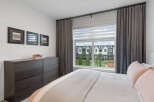 This bedroom offers a serene retreat with a large window providing abundant natural light and a view of the charming neighborhood.