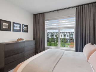 This bedroom offers a serene retreat with a large window providing abundant natural light and a view of the charming neighborhood.