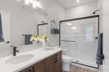 This modern bathroom features a sleek vanity with a white countertop and dark wood cabinets, complemented by a stylish black faucet.