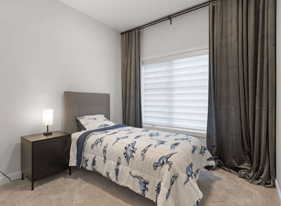 This charming bedroom features a comfortable twin bed adorned with a playful dinosaur-themed comforter, perfect for a child or guest room.