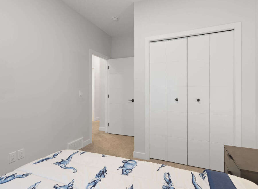 This bedroom features a comfortable bed with a playful dinosaur-themed comforter, perfect for a child's room.