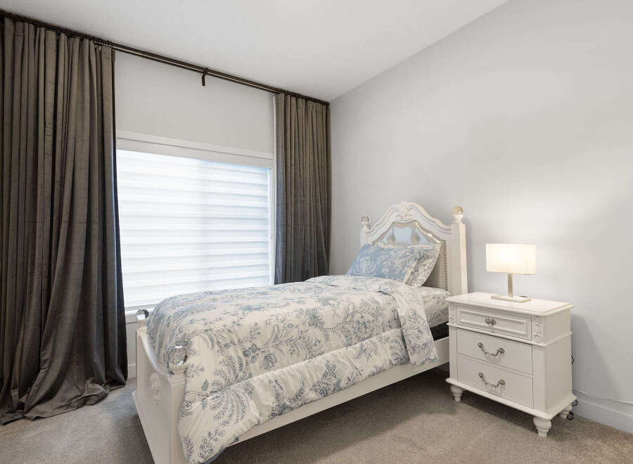 This charming bedroom features a white upholstered headboard and a matching bed frame adorned with crystal finials.