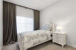 This charming bedroom features a white upholstered headboard and a matching bed frame adorned with crystal finials.